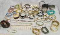 Photo showing an assortment of bracelets in various styles including bead, metal bangles, and cuffs arranged on a white cloth.