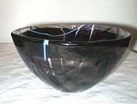 Side view of the deep purple Kosta Boda bowl showing smooth glass surface and subtle swirl patterns inside.