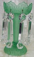 Side angle showing the carved leaf pattern on the jade green glass base and the hanging crystal prisms with round and rectangular shapes.
