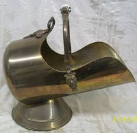 Side view of brass coal scuttle showing curved open mouth and round base