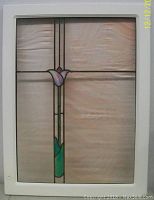 Full view of stained glass window showing the rippled light amber glass with floral design and white metal frame.