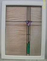 Front view of the stained glass window within the white metal frame, showing rippled glass and central floral motif.