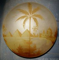 Top view of circular frosted glass lid with painted desert scene showing pyramids, palm trees, and a domed building in golden hues.