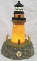 Full frontal view of the lighthouse lamp lit, showing the illuminated tower, detail on the base, and label plate reading 'Martha's Vineyard Gay Head Light MA'.