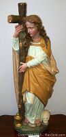 Front view of Mary Magdalene chalkware statue holding large cross, showing detailed painted features and skull at base.