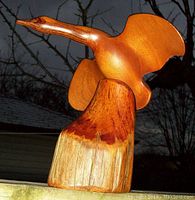 Front and side view of the wood carved Canada Goose statue mounted on a naturalistic log base showing signature and detailed wing carving.