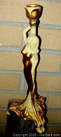 Side view of figural lady holding candle cup, showing gold and cream color scheme.