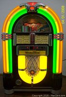 Front view of lit jukebox showing neon arches, speaker grille, Wurlitzer logo