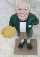 Front view of the chalkware portly butler figure showing the detailed face and the small yellow tray in the right hand.