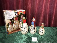 Set of three handpainted LED snowmen next to original box with packaging graphics
