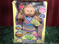 Front view of Jaylynn Sharon Cabbage Patch Kids Magic Glow Surprise doll in original box highlighting the doll's face, colorful dress, and box text.