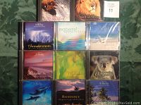 Top view of eleven CDs in jewel cases laid out on a green patterned surface. Covers show nature and relaxation themed artwork including animals, landscapes, and abstract designs.