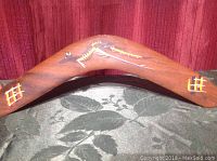 Front side of wooden boomerang showing Aboriginal-style artwork including lizard motif and painted decorations.