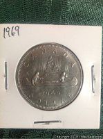 Reverse side of the 1969 Canadian silver dollar coin showing the Voyageur canoe scene and inscriptions including the year 1969.