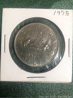 Front side of 1975 Canadian silver dollar coin showing a loon on a lake with inscriptions.