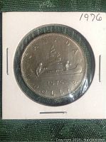 Reverse side of the 1976 Canadian silver dollar coin with voyageur canoe design and date.