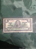 Front side of the 1937 Canadian one dollar bill with portrait of King George VI and numeric serial number 47209685.