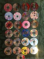Top down photo showing 25 colorful CD-ROM discs laid out in five rows. Disc titles and artwork visible indicating a mixture of games and interactive computer software.