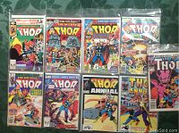 All nine Marvel Thor comic books arranged on a green surface, each in a plastic sleeve.