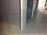 Glass table top standing vertically, showing beveled edges and corner cuts