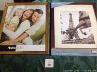 Two picture frames side by side, one gold HomeStyles frame holding a sample picture of a smiling family, the other brown frame featuring a photo of the Eiffel Tower with a label 'Easy to hang in minutes!'