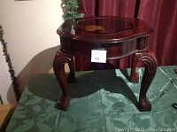 Front and side view of a vintage wooden table showing mahogany color, carved legs, and glass inset top.