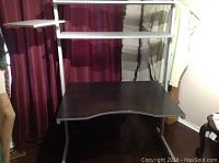 Black IKEA desk with white adjustable shelves and hinged platform in assembled state.