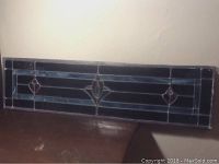 Photo of a single stained glass window with florette design showing geometric and floral patterns with blue glass colors.