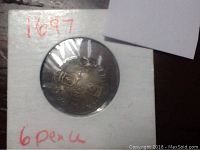 Front side of the 1697 silver coin with visible crests and hole at top.