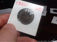 Photo of the 1880 Netherlands 2.5 cent coin held in a white cardboard holder with handwritten '1880' and '2 1/2' in red ink.