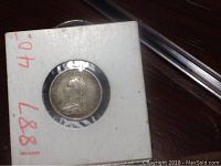 Front view of the 1887 British silver coin mounted in a white card holder showing Queen Victoria's portrait.