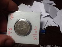 Front side of 1896 Queen Victoria silver one shilling coin in holder with visible wear on the portrait.