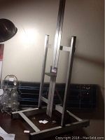 Full view of lightweight aluminum artist easel standing on a desk with visible base support frame.