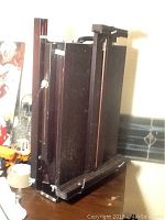 Closed view of dark wood artist easel box standing upright showing side profile and handle on top.