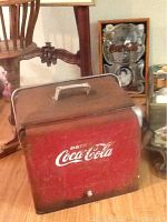 Full view of the red Coca Cola metal cooler showing the front logo and hinged lid with handle.