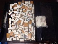 Closer look inside the open vinyl case showing a variety of mah jong tiles made of bamboo and plastic, white score sticks wrapped in plastic on the right.
