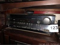 Front view of Onkyo receiver with HDMI and input buttons visible, dusty surface, portion of remote control on top.