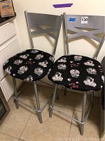 Pair of silver metallic framed swivel bar stools with black Betty Boop printed cushioned seats and crossed backrests
