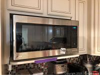 Stainless steel LG microwave mounted over stove with control panel visible on the right side and door closed.