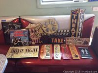 Photo of the assortment of movie theater wall decor displayed on a red booth, including various tin and wood signs, and framed posters.