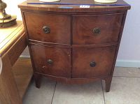 Front view of the antique wooden side table showing four curved front doors with round metal handles.