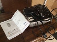 Photo of the InFocus projector with cables and remote control along with the setup guide on a wooden surface.