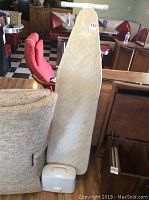 Wireless Sunbeam iron in white carrying case with handle next to padded ironing board.