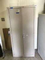 Front view of the light grey metal storage cabinet showing double doors and lockable handle.