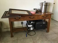 Full view of wooden entry table with three drawers and various items on top and underneath (items not included)