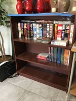 Full view of wooden bookcase with Stephen King books and boxed Harry Potter books on top shelf and additional books on second shelf