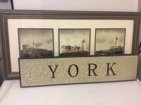 Pair of coastal themed wall art pieces: framed triptych of lighthouse prints by Doug Brega and a rectangular wooden sign that reads 'YORK'.