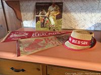 Full lot including the vintage Red Sox boater hat, two 1967 pennants and the vinyl record displayed on a countertop