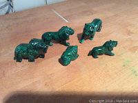 Top view showing all 5 malachite lion figurines arranged on wooden surface