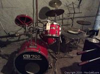Full drum kit including bass drum, snare drum, two toms, hi-hat cymbal, two additional cymbals, drumsticks and practice pad with music stand visible.